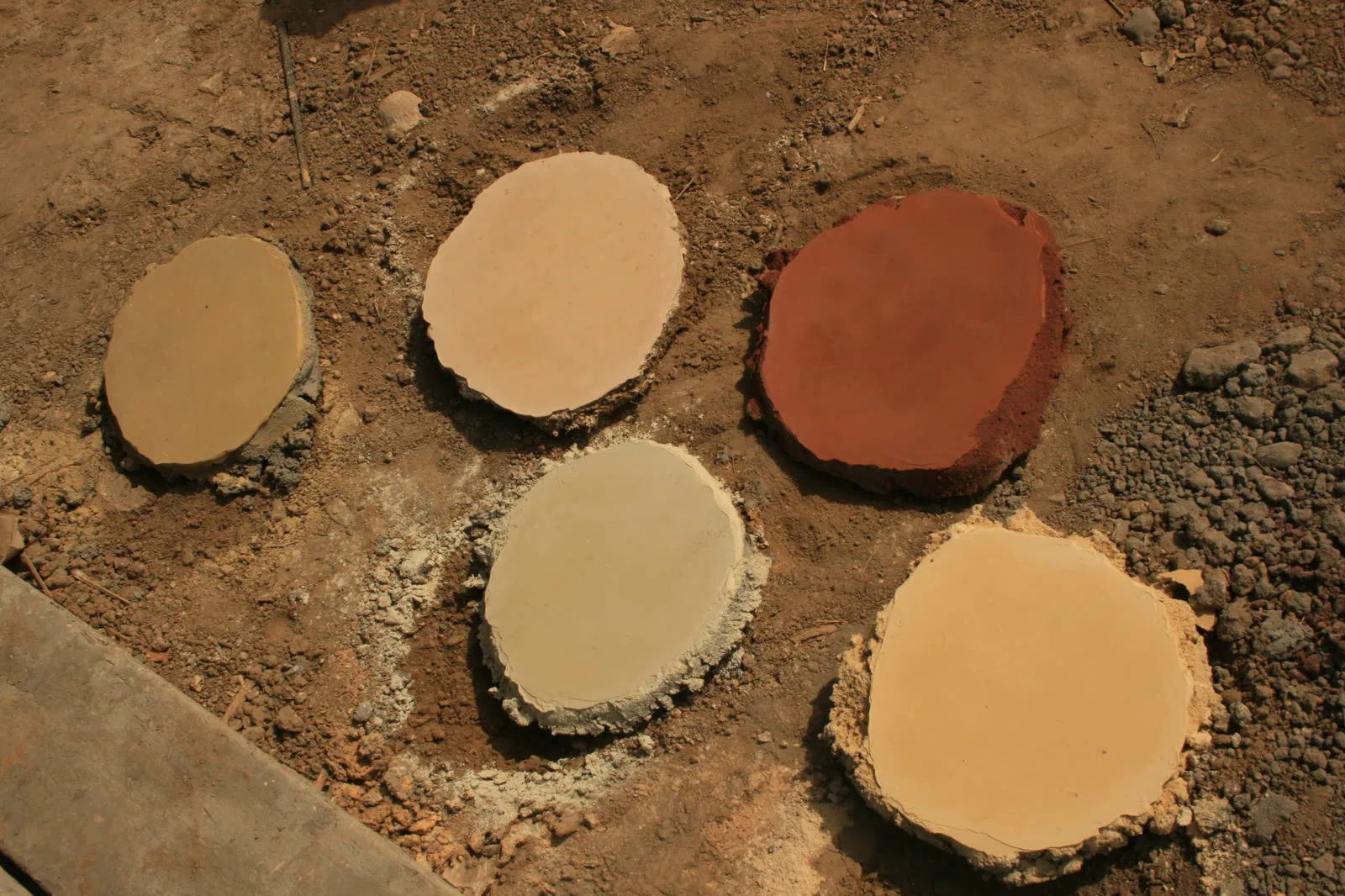 Muestras de ocre en cemento curándose sobre la tierra de la obra